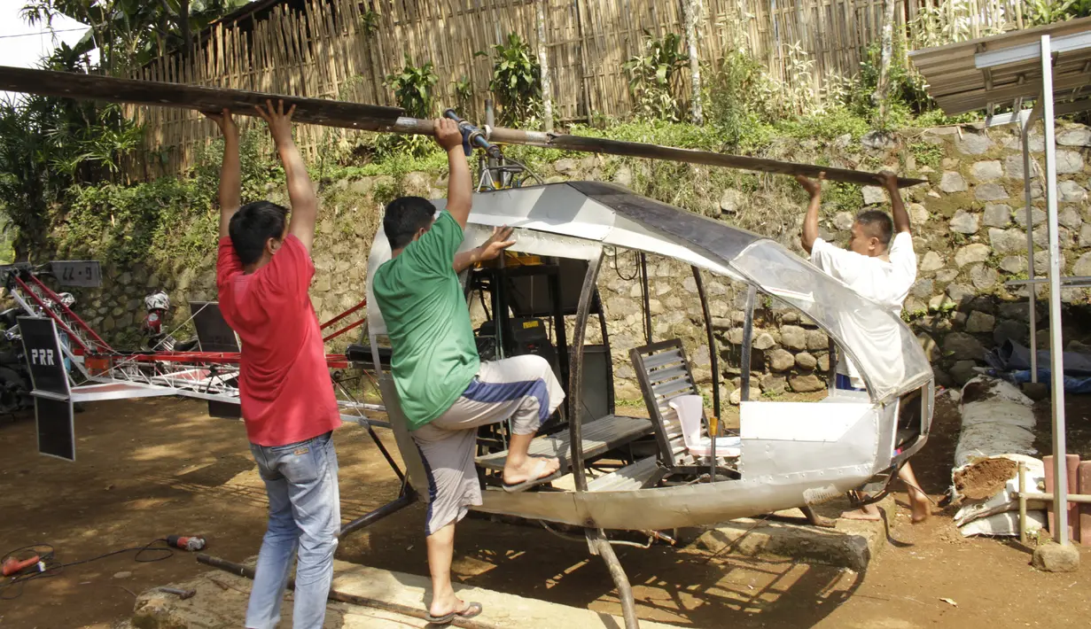 Gambar yang diambil pada 17 November 2019, Jujun Junaedi (kanan) menyelesaikan pembuatan helikopter buatannya di halaman belakang rumahnya di Sukabumi. Jujun yang berusia 41 tahun ini menargetkan helikopter berbahan bakar bensinnya rakitannya dapat diuji terbang pada akhir 2019. (Wulung WIDARBA/AFP)