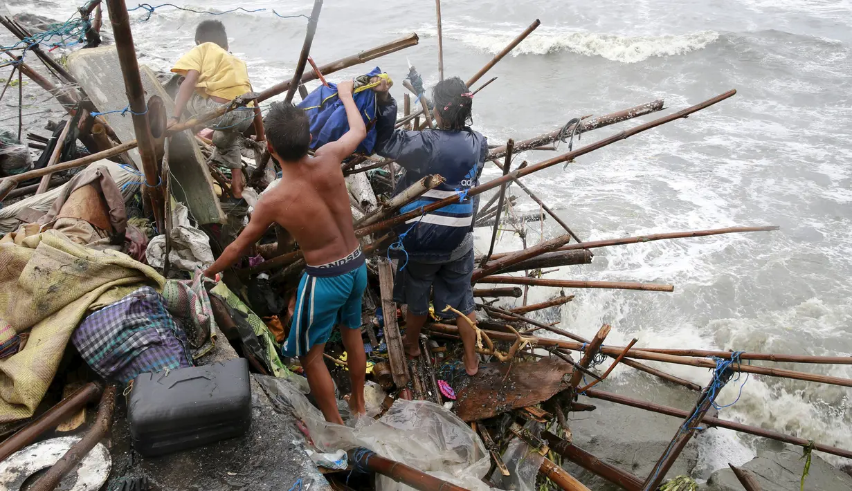 Keluarga Taroyo yang tinggal di sepanjang pantai Teluk Manila mencari barang yang bisa diselamatkan setelah rumah mereka rusak akibat Topan Koppu, Minggu (18/10). Topan Koppu melanda Filipina timur laut dan merusak rumah-rumah. (REUTERS/Romeo Ranoco)