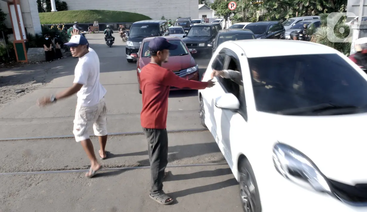 Warga mengatur lalu di perlintasan kereta api di Jalan Duri Kosambi Raya, Jakarta, Rabu (15/1/2020).  Warga setempat membangun palang secara swadaya dan mengatur lalu lintas akibat perlintasan kereta dekat  Stasiun Rawa Buaya tersebut belum dipasang palang pintu otomatis. (merdeka.com/Iqbal Nugroho)