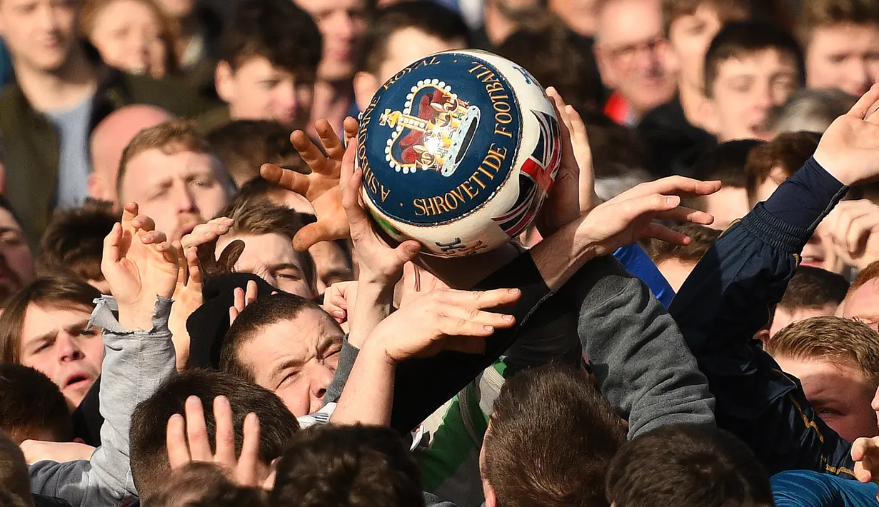Para peserta berebut bola saat mengikuti Royal Shrovetide Football Match di Ashbourne, Derbyshire, Inggris, Selasa (5/3). Royal Shrovetide Football Match merupakan permainan sejenis sepak bola bercampur rugby. (Oli Scarff/AFP)