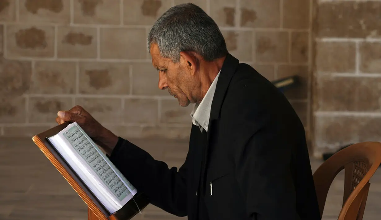 Seorang pria membaca ayat-ayat Alquran saat menunggu waktu berbuka puasa selama bulan suci Ramadhan di Masjid Al-Omari, Kota Gaza, Palestina, 13 April 2022. (AP Photo/Adel Hana)