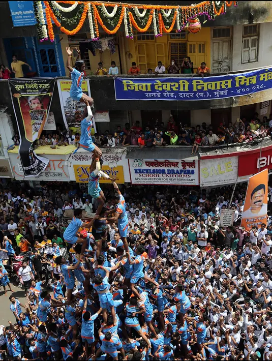 Umat Hindu membentuk piramida manusia selama Festival Janmashtami di Mumbai, India, 24 Agustus 2019. Piramida manusia itu untuk memecahkan pot berisikan suus yang menggangtung di langit-langit rumah supaya bisa diambil isinya. (AP Photo/Rajanish Kakade)