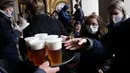 Orang-orang mengantre untuk minum bir di teras restoran di Praha, Republik Ceko, Senin, (11/5/2020). Bar, restoran, kafe yang menawarkan tempat duduk terbuka mulai melayani konsumen pertama mereka sejak 14 Maret. (AP/Petr David Josek)