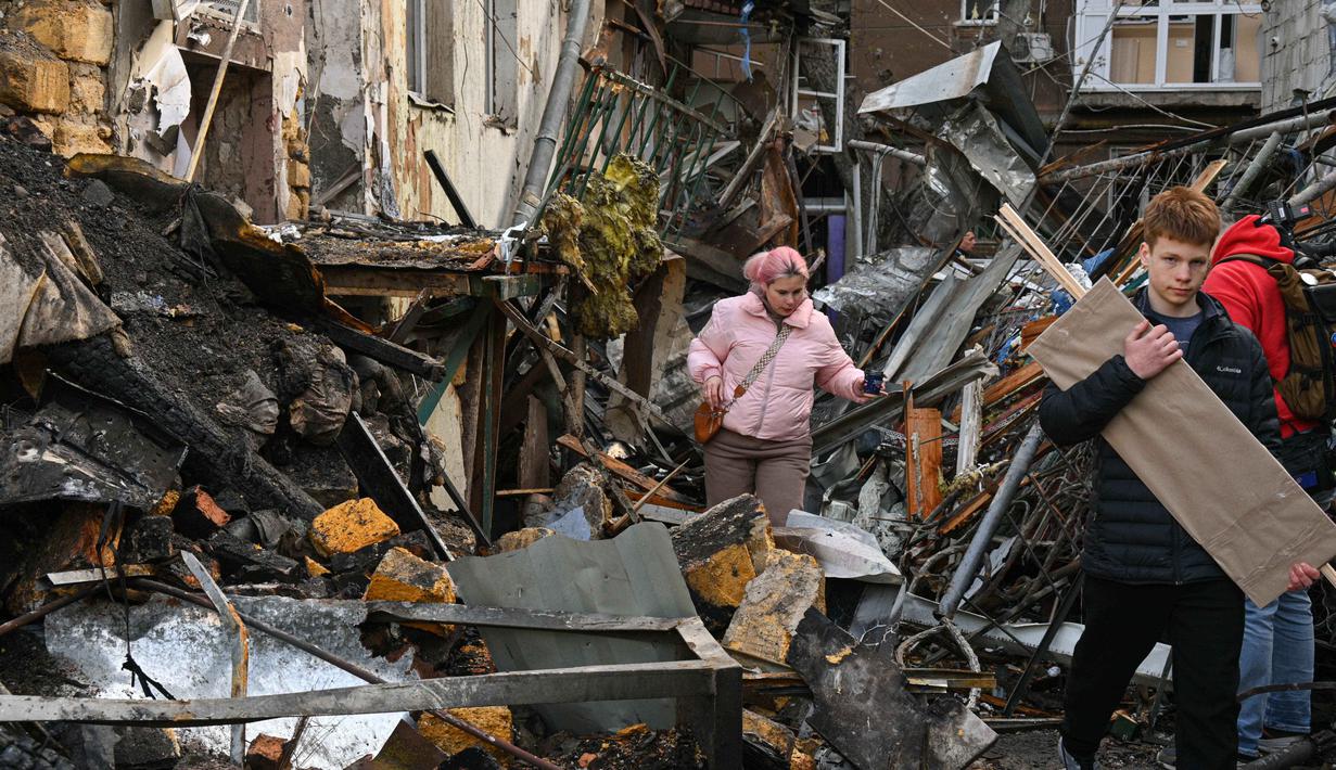 Warga setempat berjalan di halaman sebuah lingkungan perumahan yang rusak parah setelah serangan Rusia di Odesa, Ukraina, Jumat 24 April 2026. Gelombang serangan udara Rusia yang menggunakan kombinasi pesawat nirawak (drone) dan rudal kembali menghantam jantung permukiman warga Ukraina. (AP Photo/Michael Shtekel)