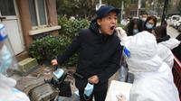 Seorang pria menjalani tes asam nukleat untuk virus corona Covid-19 di Wuhan di provinsi Hubei China tengah, Selasa (22/2/2022). Wuhan, wabah besar pertama dari pandemi virus corona melaporkan lebih dari selusin kasus virus corona baru minggu ini. (AFP/STR)