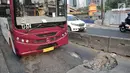 Bus Transjakarta melintas di jalan Galunggung yang rusak dan berlubang di Setia Budi, Jakarta, Selasa (30/7/2019). Jalan yang rusak tersebut mengakibatkan bus melaju dengan kecepatan lambat. (merdeka.com/Iqbal S Nugroho)