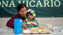 Imigran Guatemala Maudelina Geronimo memberi makan putrinya yang berusia tiga tahun Lisbeth di tempat penampungan yang dikelola pemerintah di Ciudad Juarez, Meksiko, 18 Desember 2022. Kota-kota perbatasan Texas bersiap menghadapi lonjakan sebanyak 5.000 imigran baru setiap hari yang melintasi perbatasan AS-Meksiko karena pembatasan imigrasi era pandemi berakhir minggu ini. (AP Photo/Andres Leighton)