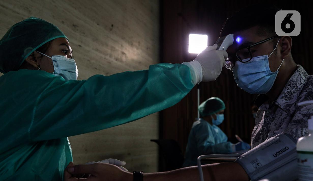 Tenaga medis mengukur suhu tubuh karyawan Emtek Grup sebelum mengikuti vaksinasi COVID-19 di Hall SCTV Tower, Senayan City, Jakarta, Jumat (4/6/2021).  Vaksinasi Gotong Royong pendanaannya dibebankan kepada badan hukum atau badan usaha. (Liputan6.com/Johan Tallo)