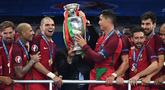 Pemain Timnas Portugal, Cristiano Ronaldo dan Pepe menerima trofi Piala Euro setelah mengalahkan Prancis di final Piala Euro 2016 yang berlangsung di Stade de France, Paris, (10/7/2016). (AFP/Franck Fife)