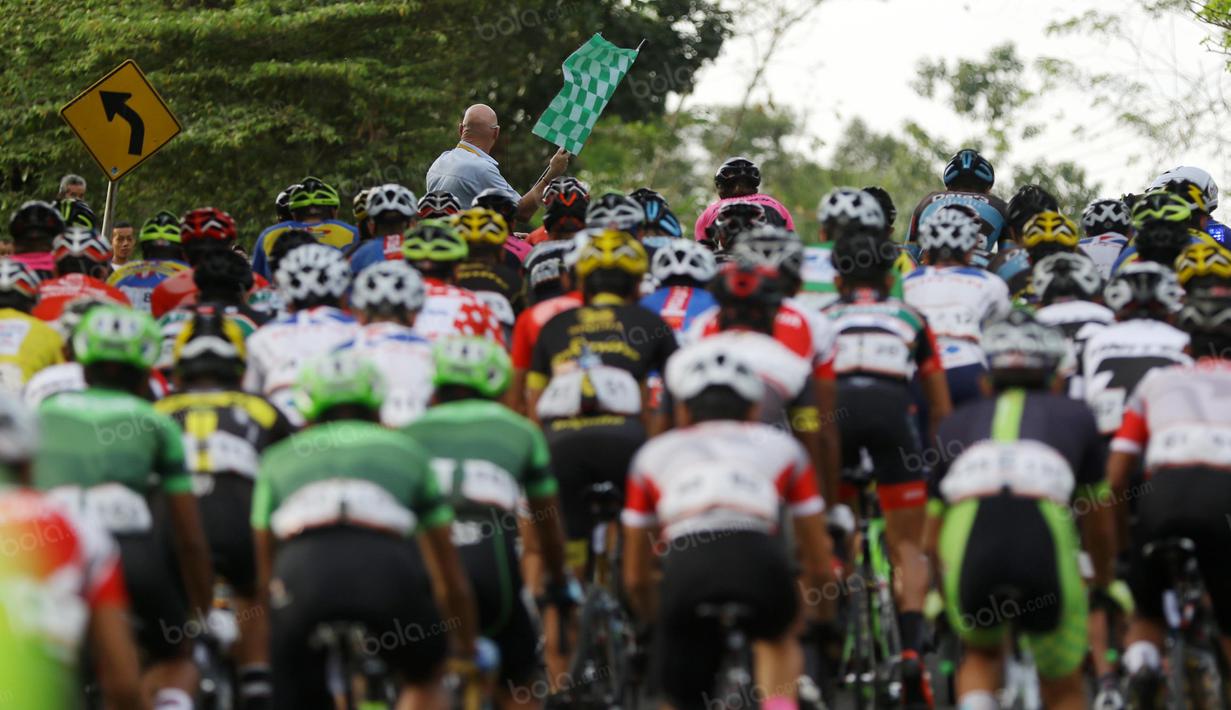 Race Director mengangkat bendera sebelum start pada etape 7 Tour de Singkarak 2016 di Kabupaten Sijunjung, Jumat (12/8/2016). (Bola.com/Nicklas Hanoatubun)