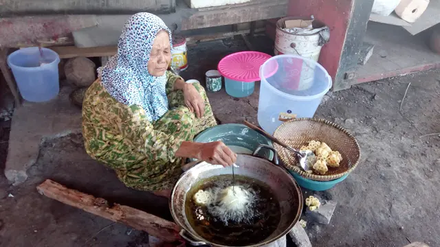 Mak Atimah, nampak telaten memasukan bahan seroja dalam sebuah catel penggorengan, untuk menghasilkan kue seroja yang renyah dan krenyes, sebagai makanan khas lebaran