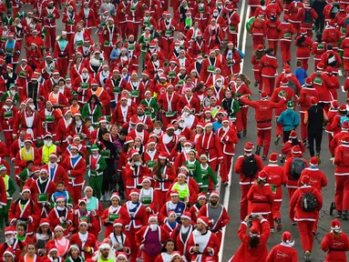 Orang-orang mengenakan kostum Sinterklas ambil bagian dalam Santa Claus Run di Madrid, Spanyol, Minggu (9/12). Ribuan orang berjalan dan berlari dalam perlombaan Santa tahunan melintasi jalan-jalan ibu kota Spanyol. (Gabriel BOUYS / AFP)