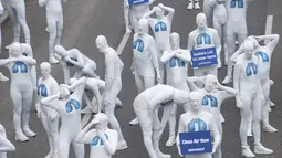 Aktivis dari Greenpeace mengenakan pakaian serba putih melakukan aksi teatrikal saat turun ke jalan di Stuttgart, Jerman (19/2). Mereka melakukan aksi memprotes polusi yang diakibatkan oleh knalpot mobil diesel. (Sebastian Gollnow/dpa/AFP)