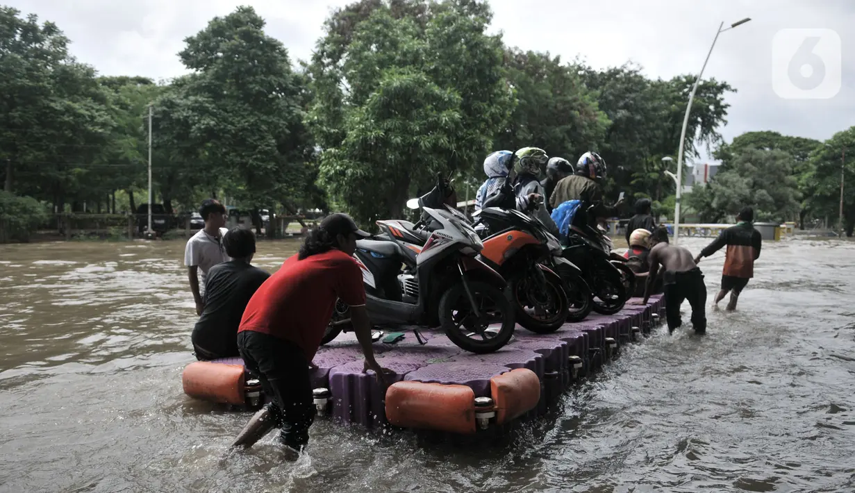 Pengendara sepeda motor menggunakan jasa rakit saat banjir melanda Cempaka Putih, Jakarta, Minggu (23/2/2020). Pengendara memanfaatkan jasa angkutan rakit yang ditawarkan warga agar dapat melewati banjir. (merdeka.com/Iqbal S. Nugroho)