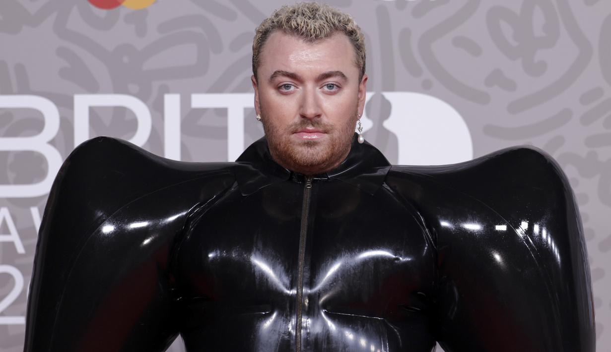 Sam Smith berpose untuk fotografer setibanya pada karpet merah Brit Awards 2023 di London, Sabtu (11/2/2023). Pelantun ‘Unholy’ ini memakai gaun unik berwarna hitam, lengkap dengan sepatu heels dan sarung tangan berwarna senada. (Photo by Vianney Le Caer/Invision/AP)