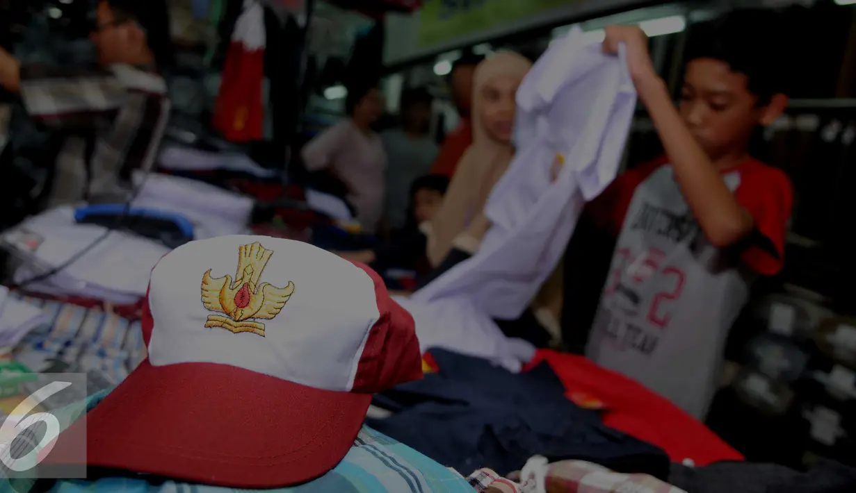 Calon pembeli melihat baju seragam yang dijual di Pasar Senen, Jakarta, Selasa (12/7). Penjualan seragam sekolah menjelang tahun ajaran baru mengalami peningkatan sekitar 30-50 persen dari hari biasa. (Liputan6.com/Gempur m Surya)