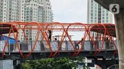 Pekerja menyelesaikan pembangunan jembatan penyeberangan orang (JPO) atau "Skywalk" di kawasan Kebayoran Lama, Jakarta, Sabtu (19/11/2022). Pemprov DKI Jakarta melalui Dinas Bina Marga DKI Jakarta membangun skywalk sepanjang 500 meter dengan desain dan cahaya artistik serta dilengkapi fasilitas lift juga eskalator. (Liputan6.com/Angga Yuniar)