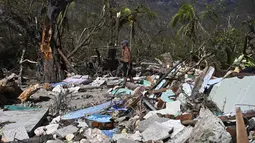 Seorang pria berjalan di tengah puing-puing rumah yang rusak akibat Badai Melissa di desa Boca de Dos Rios, provinsi Santiago de Cuba, Kuba pada Kamis 30 Oktober 2025. Sehari sebelumnya, atau Selasa (28/10/2025), badai ini menghantam Jamaika sebagai badai Kategori 5 yang sangat kuat. (YAMIL LAGE/AFP)