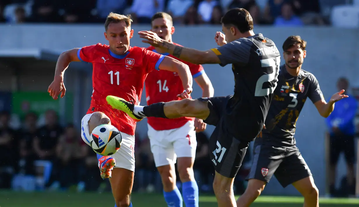 Penyerang Republik Ceko #11 Jan Kuchta dan gelandang Makedonia Utara #21 Jani Atanasov bersaing memperebutkan bola dalam laga uji coba terakhir jelang EURO 2024 di Malsovicka Arena, Hradec Kralove, Senin (10/6/2024) malam WIB. (Michal Cizek / AFP)