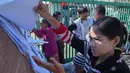 Sebagai informasi, Myanmar, yang berpenduduk sekitar 50 juta jiwa, masih terbelah gara-gara perang saudara. Tampak dalam foto, orang-orang mencari nama mereka di daftar pemilih yang dipajang di luar tempat pemungutan suara di Naypyitaw, Myanmar, Minggu, 28 Desember 2025. (AP Photo/Aung Shine Oo)