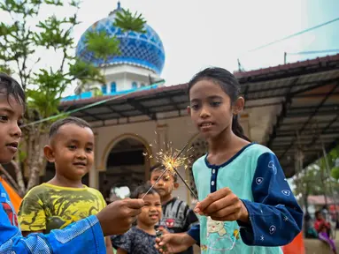 Anak-anak bermain kembang api di dekat tenda-tenda yang didirikan untuk para korban banjir di kompleks sebuah masjid, Meurah Dua, Kabupaten Pidie Jaya, Provinsi Aceh, pada 21 Februari 2026, setelah banjir dan tanah longsor dahsyat melanda Sumatra, akhir November 2025 lalu. Bulan Ramadan 1447 Hijriah atau 2026 Masehi dijalani dengan penuh keprihatinan oleh warga di Kabupaten Pidie Jaya, Provinsi Aceh. (CHAIDEER MAHYUDDIN/AFP)