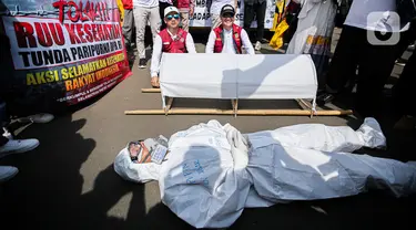 Pengunjuk rasa dari tenaga medis dan kesehatan melakukan aksi teatrikal di depan gedung MPR/DPR-DPD, Senayan, Jakarta, Selasa (11/7/2023). (Liputan6.com/Faizal Fanani)