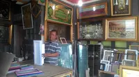 Ismail, salah satu pengrajin sekaligus pengusaha pigura asal kampung Cijambe di bengkel piguranya, dengan berbagai hasil bingkai olah tangannya (Liputan6.com/Jayadi Supriadin)