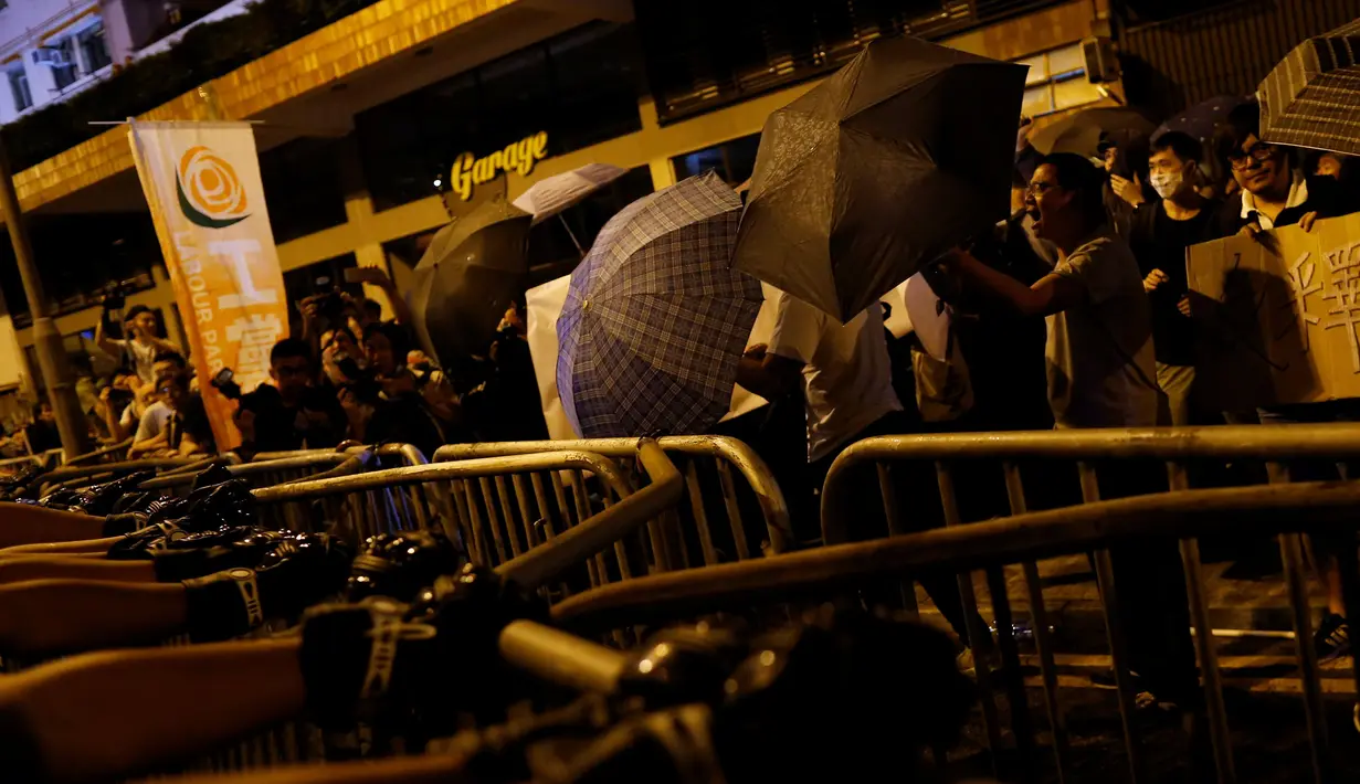 Massa menggunakan payung untuk menghindar dari semprotan merica oleh polisi di Hong Kong, Minggu (6/10). Massa berdemonstrasi menentang intervensi Bejing untuk melarang dua aktivis pro-kemerdekaan menjabat sebagai anggota parlemen. (REUTERS/Tyrone Siu)