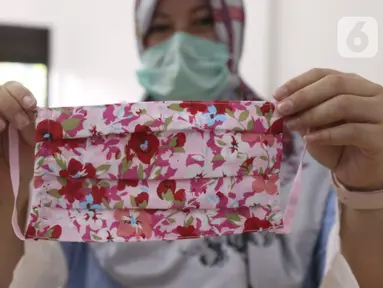 Seorang ibu memperlihatkan masker dari bahan kain yang diproduksi di Balai Latihan Kerja (BLK) Larangan, Tangerang, Senin (6/4/2020). Pemkot Tangerang memproduksi sendiri masker kain untuk didistribusikan ke wilayah Tangerang guna mencegah penyebaran virus corona Covid-19 (Liputan6.com/Angga Yuniar)