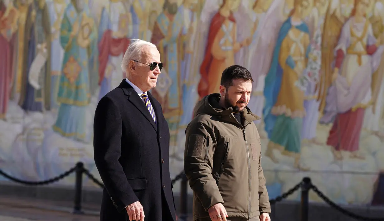 Presiden Ukraina Volodymyr Zelensky (kanan) bersama Presiden AS Joe Biden (tengah) saat setelah tiba di Kyiv, Ukraina pada 20 Februari 2023. Keduanya mengunjungi Wall of Remembrance of the Fallen for Ukraine di Kyiv. Kunjungan Biden dilakukan jelang peringatan satu tahun invasi Rusia. (Dimitar DILKOFF/AFP)