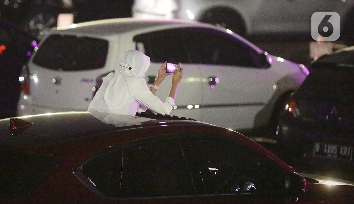 Seorang wanita mengabadikan penampilan Kahitna dalam konser New Live Experience 2020 di Parkir Barat JIExpo Kemayoran, Jakarta, Sabtu (29/8/2020). Pertunjukan diawali dengan lagu Padamu Negeri ini disambut para Soulmate, sebutan bagi penggemar Kahitna. (Fimela.com/Bambang E.Ros)