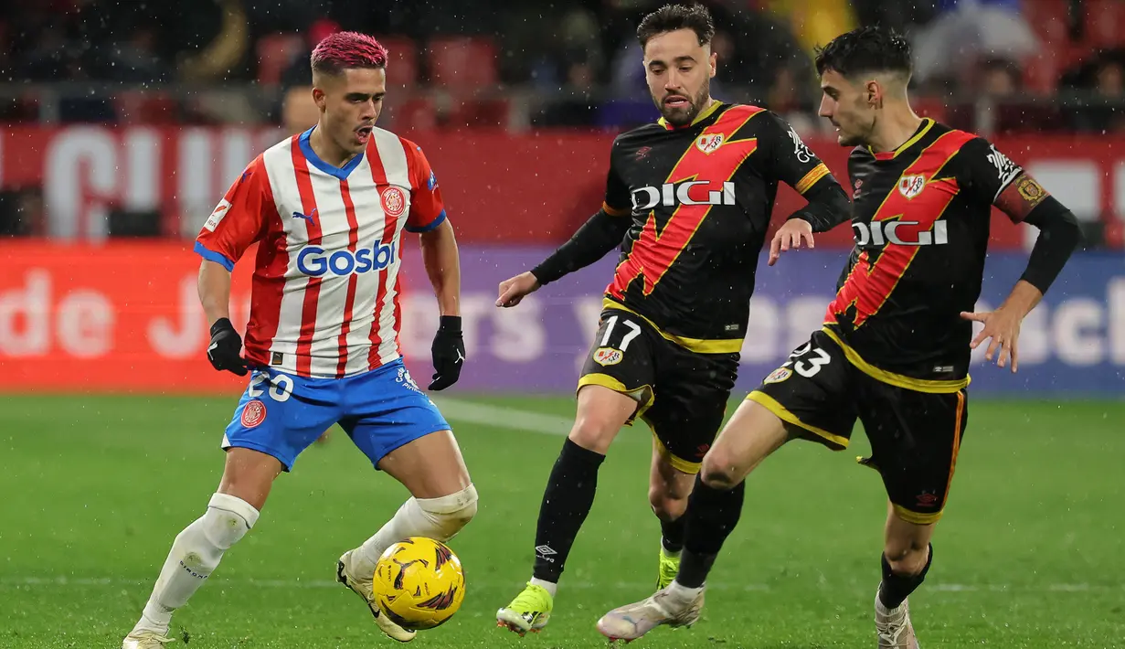 Pemain Girona, Yan Couto (kiri) berusaha melewati penjagaan sejumlah pemain Rayo Vallecano pada laga lanjutan Liga Spanyol 2023/2024 di Montilivi Stadium, Girona, Spanyol, Selasa (27/02/2024). (AFP/Lluis Gene)