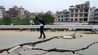 Sejumlah warga Kathmandu melihat jalan yang rusak akibat gempa , Minggu (26/4/2015). Gempa berkekuatan 7,8 Skala Richter dikabarkan telah menelan korban sekitar 2000 jiwa. (AFP Photo/Prakash Mathema)