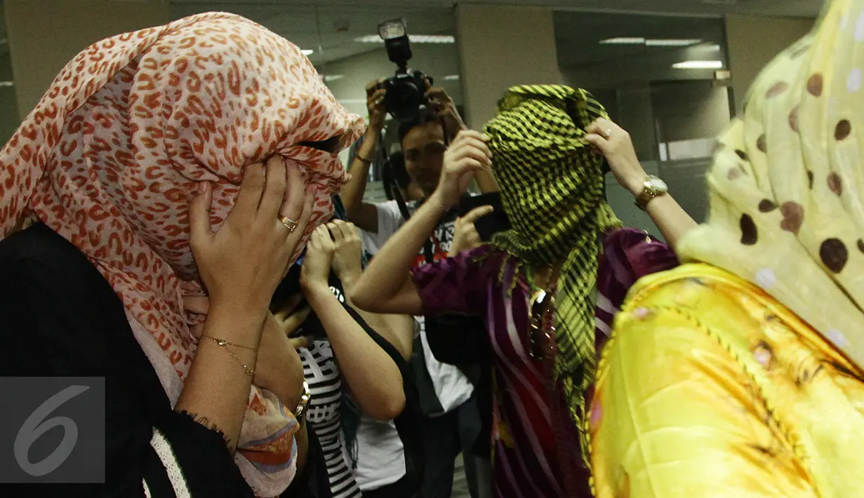 Para wanita asal Maroko menutupi wajahnya saat berada di kantor Imigrasi, Jakarta, Kamis (11/6/2015). Dalam keterangannya, pihak Imigrasi mengamankan sejumlah wanita yang diduga PSK asal Maroko di Bogor, beberapa waktu lalu. (Liputan6.com/Johan Tallo)