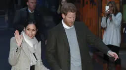 Meghan Markle melambaikan tangan saat kunjungan Pangeran Harry ke stasiun radio Reprezent 107,3 FM di Brixton, London, Selasa, (9/1). Kunjungan ini untuk melihat pekerjaan stasiun radio yang mendukung kreatifitas pemuda. (AP Photo/Dominic Lipinski, Pool)