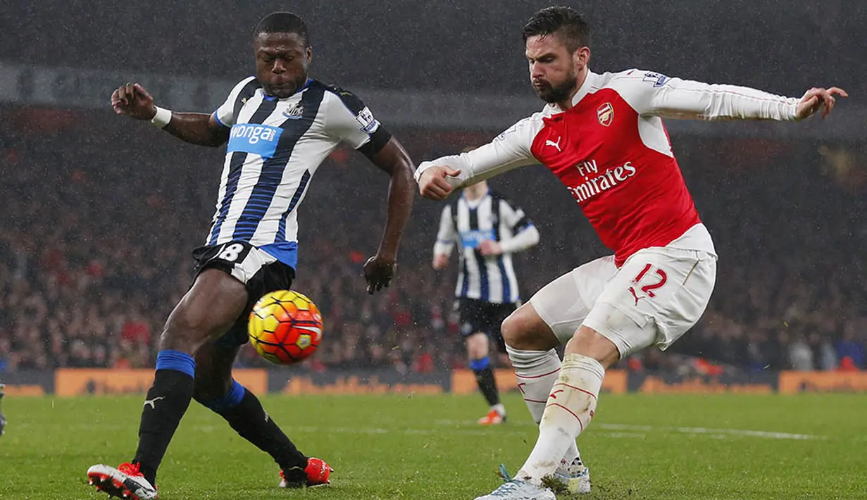 Striker Arsenal, Olivier Giroud, dihadang pemain Newcastle, Chancel Mbemba, ketika akan mengirim umpan pada laga Liga Premier Inggris. Berkat kemenangan itu Arsenla kian kokoh di puncak klasemen. (Reuters/Eddie Keogh)