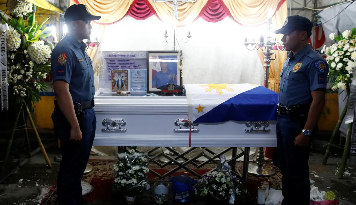 Dua petugas kepolisian berjaga di dekat peti jenazah rekannya, Rancel Cruz yang tewas oleh pecandu narkoba di Manila, Filipina, (19/10). Sebanyak 1.900 orang tewas akibat perang narkoba di Filipina. (REUTERS/Erik De Castro)