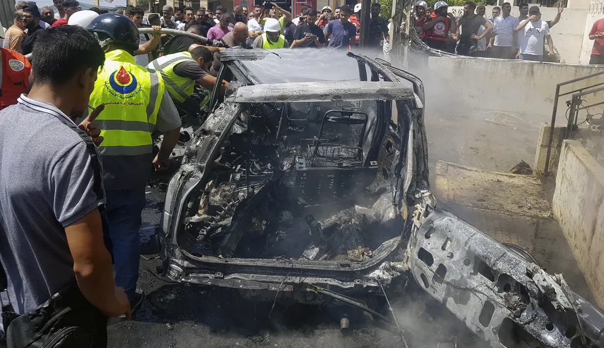 Pekerja Pertahanan Sipil memeriksa sisa-sisa mobil yang terbakar yang dilaporkan menjadi sasaran serangan pesawat tak berawak atau drone Israel di kota pelabuhan selatan Sidon, Lebanon, Senin (26/8/2024). (AP Photo/Mohammed Zaatari)
