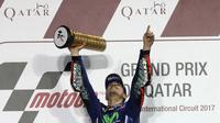 Pebalap Movistar Yamaha, Maverick Vinales, mengangkat pialanya usai memenangi MotoGP Qatar. Mantan pebalap Suzuki Ecstar tersebut kini memimpin klasemen MotoGP dengan perolehan 25 poin. (AFP/Karim Jaafar)
