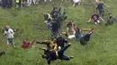 Sejumlah peserta berlari menuruni bukit curam untuk mengejar keju dalam kompetisi Cheese Rolling di Cooper's Hill di Brockworth, Gloucestershire, Inggris, Senin (28/5). Kompetisi ini diikuti ribuan peserta setiap tahunnya. (Aaron Chown/PA via AP)