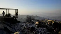 Penduduk menyaksikan rumah-rumah yang terbakar dan puing-puing lainnya setelah kebakaran hutan mencapai lingkungan Villa Independencia di Vina del Mar, Chile, Sabtu, 3 Februari 2024. ( Esteban Felix/AP)