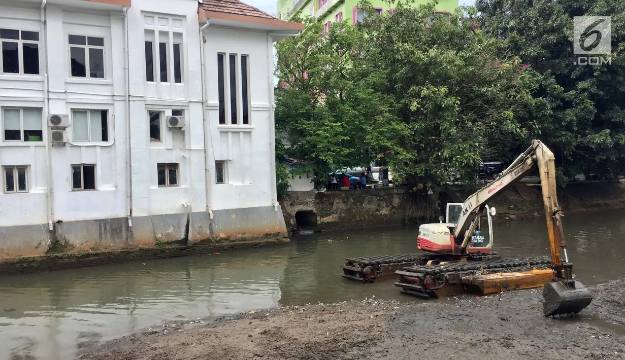 Pekerja menggunakan alat berat untuk mengeruk lumpur dan sampah yang mengendap di anak Sungai Ciliwung, Jakarta, Jumat (26/1). (Liputan6.com/Immanuel Antonius)