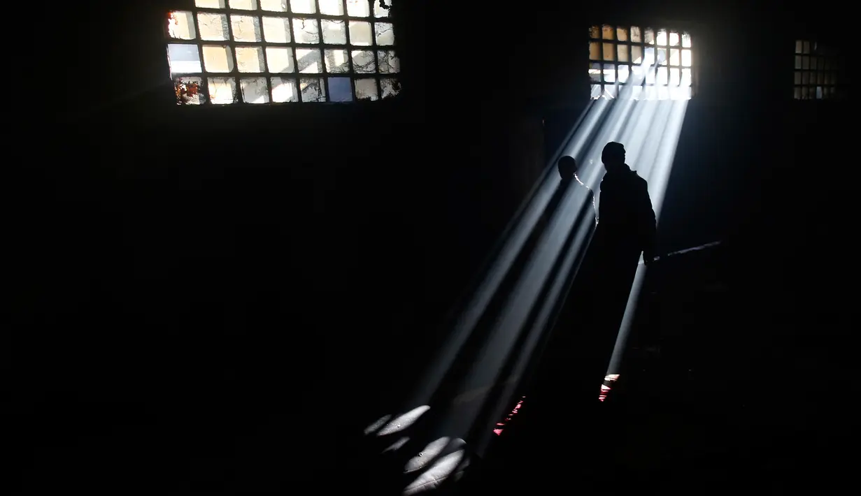 Dua orang imigran berjalan di sebuah gudang kosong di Belgrade, Serbia (8/1). Mereka harus bertahan hidup dibawah salju dingin dengan suhu -15 derajat Celcius. (AP Photo/Darko Vojinovic)
