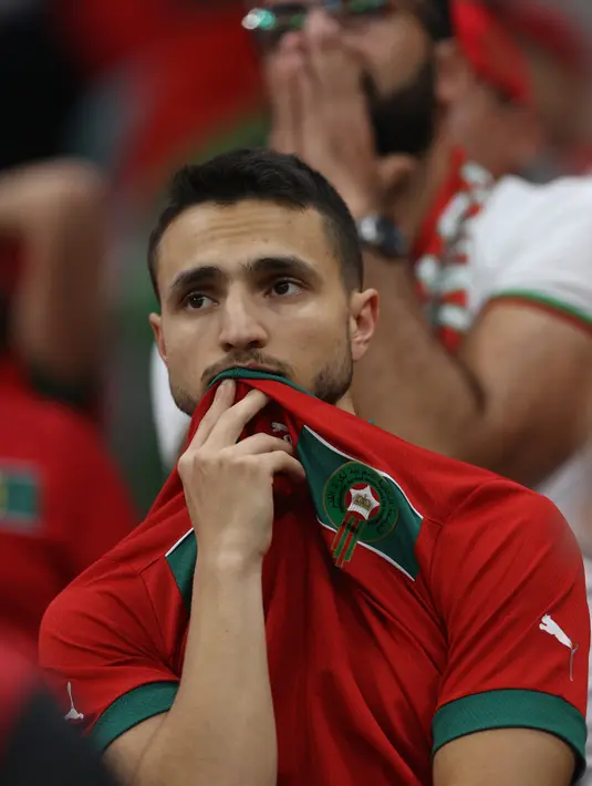 Ekspresi sedih seorang suporter Maroko setelah tim yang didukung kalah 0-2 dalam pertandingan sepak bola semifinal Piala Dunia Qatar 2022 antara Prancis dan Maroko di Stadion Al-Bayt di Al Khor, Doha, Qatar, Kamis (15/12/2022). Pertandingan kali ini Maroko lebih banyak menguasai bola di awal pertandingan. (ADRIAN DENNIS / AFP)