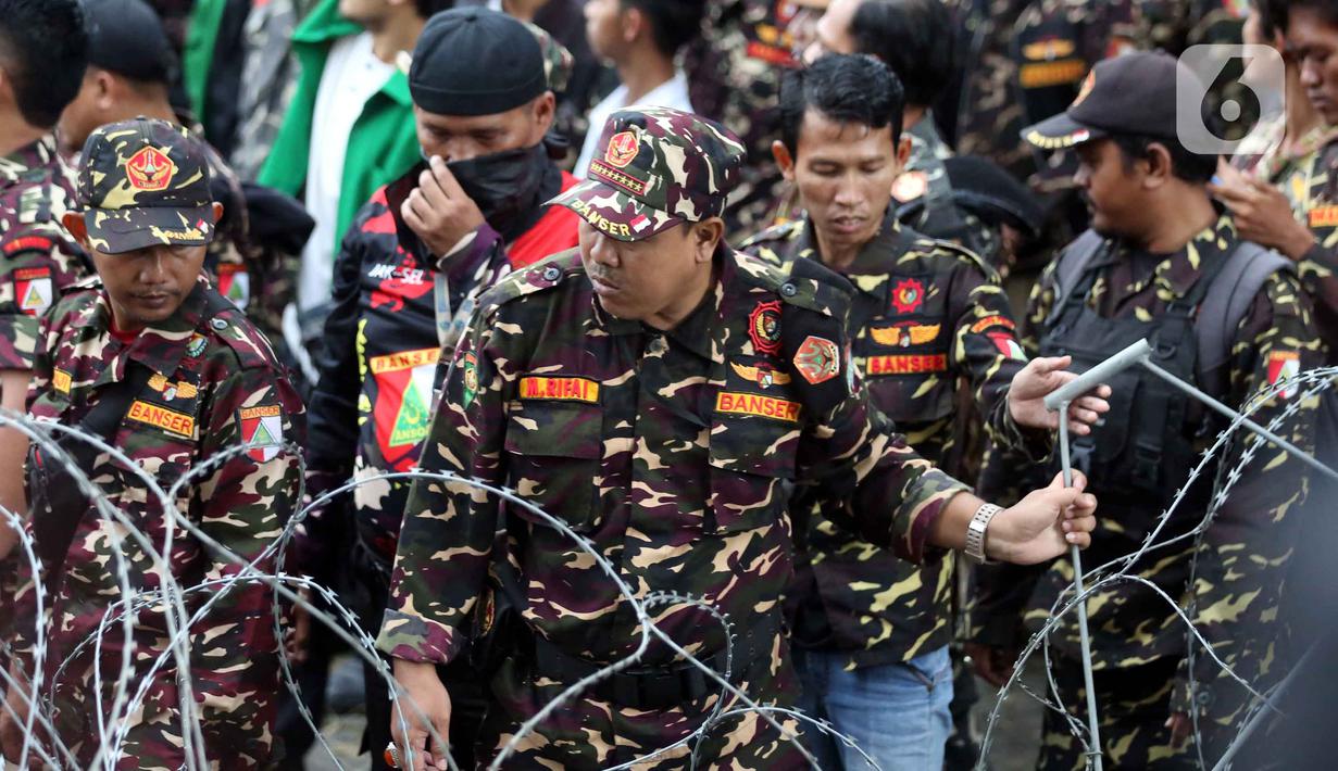 Penahanan dilakukan usai Yaqut Cholil Qoumas diperiksa oleh penyidik sejak sekitar pukul 13.00 WIB. Tampak dalam foto, anggota dan simpatisan Barisan Ansor Serbaguna (Banser) saat berunjuk rasa di depan gedung Merah Putih Komisi Pemberantasan Korupsi (KPK), Jakarta, Kamis (12/3/2026). (Liputan6.com/Helmi Fithriansyah)