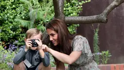 Duchess of Cambridge Kate Middleton bersama seorang anak saat ikut serta belajar fotografi dengan Action for Children di Kingston upon Thames, Inggris (25/6/2019). (AFP Photo/Chris Jackson)