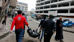 Petugas medis membawa mayat korban ledakan bom di sebuah pasar di Baghdad, Irak (31/12). Diketahui dua bom meledak, dan salah satunya diyakini sebagai bom bunuh diri. (Reuters/Ali al-Mashhadan 