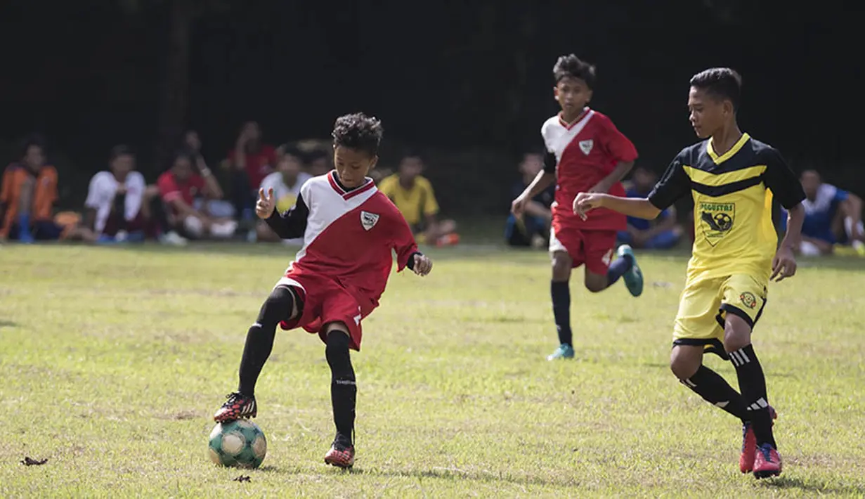 Seorang pesepak bola muda mencoba menggiring bola saat bertanding disaksikan pelatih Bali United, Indra Sjafri, di Lapangan MAN Insan Cendikia, Tangerang, Jumat (8/1/2016). (Bola.com/Vitalis Yogi Trisna)