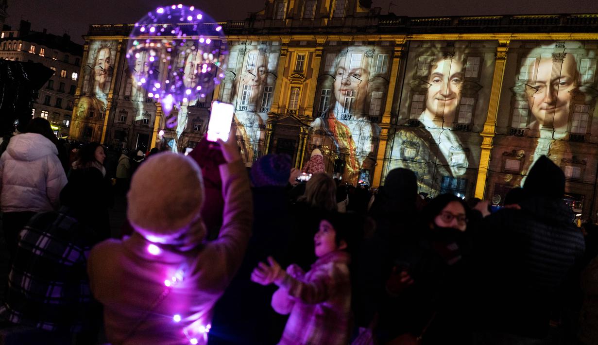 Orang-orang menghadiri pertunjukan cahaya malam di Lyon, Prancis, 8 Desember 2022. Jutaan orang diperkirakan akan menyaksikan acara Festival Cahaya selama empat hari di kota tersebut. (AP Photo/Laurent Cipriani)