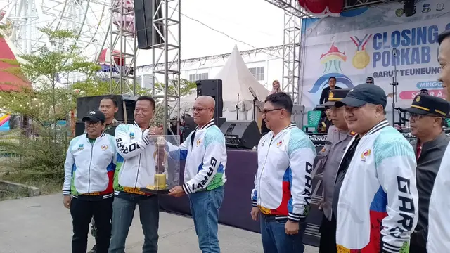 Sekda Garut Nurdin Yana disaksikan Ketua KONI Garut dan Mantan Bupati Garut, memberikan piala bergilir kepada Camat Tarogong Kidul sebagai juara umum Porkab Garut 2024. (Liputan6.com/Jayadi Supriadin)